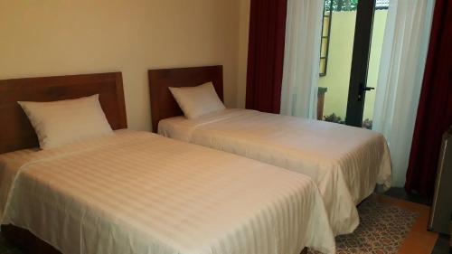 two beds sitting next to each other in a room at Pink Tulip Hoi An in Hoi An
