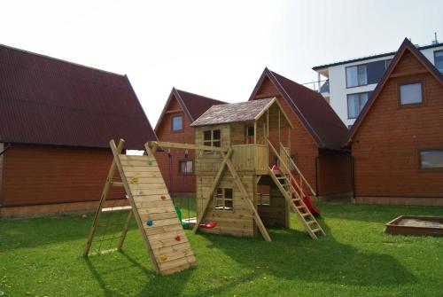 a wooden play set in a yard next to a house at Rega domki in Sarbinowo