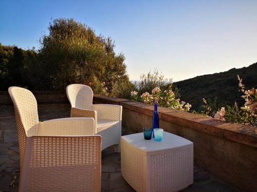 a patio with two chairs and a table with a vase on it at S'Abba Druche rooms in Bosa