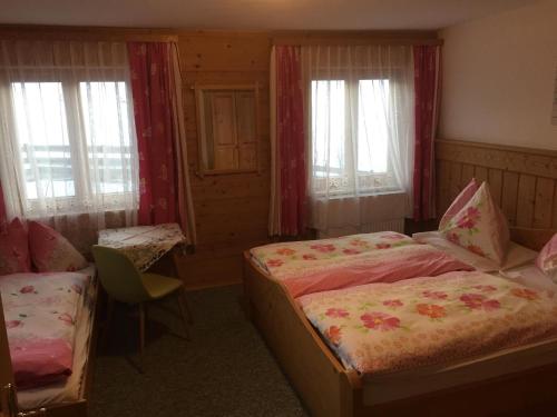 a bedroom with two beds and a chair and windows at Nagellehen in Flachau