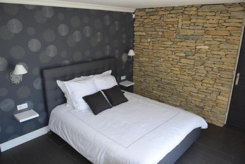 a bedroom with a white bed with a brick wall at Le Mazet d'Emilia avec jardin et piscine privés in Cucuron