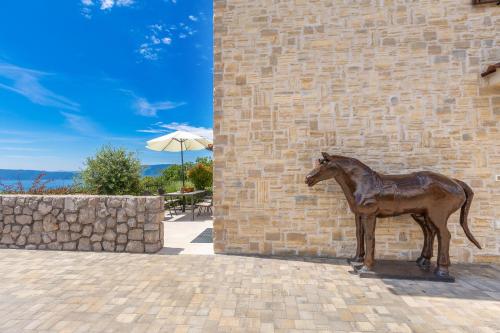 a statue of a horse standing next to a brick wall at Villa Cavallo in Linardići