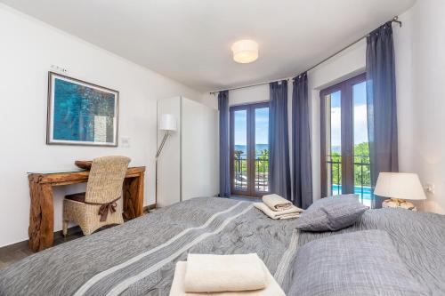 a bedroom with two beds and a desk and windows at Villa Cavallo in Linardići