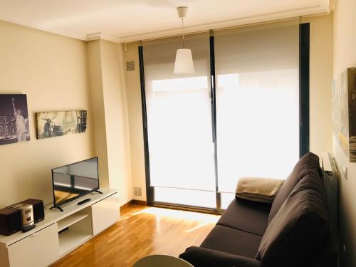 a living room with a couch and a television at Apartamento Bonitas Vistas in Luanco