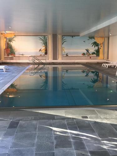 a large swimming pool with blue water in a building at Laax Rancho Residence in Laax