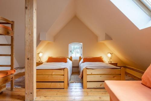 sypialnia na poddaszu z 2 łóżkami i oknem w obiekcie Vila Josefina Jizerské hory w mieście Josefuv dul