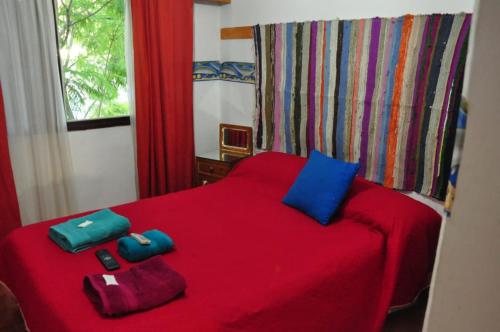 a red bed with two blue pillows on it at Hotel La Marina in Villa Carlos Paz