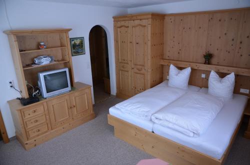a bedroom with a large bed and a tv at Apartmenthaus Bader in Leutasch