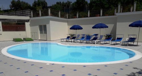 a large swimming pool with blue chairs and umbrellas at Central Park in Massa Lubrense