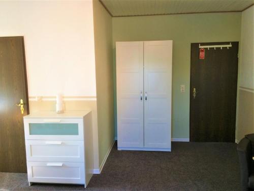 pusty pokój z białą szafką i szafą w obiekcie Huus Störtebeker w mieście Dornumersiel