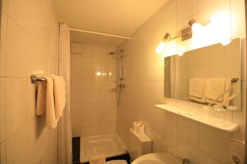 a white bathroom with a toilet and a sink at Landgasthof Auerschmiede in Irschenberg