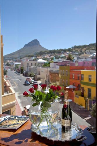 a bottle of wine and a vase with flowers on a table at Rouge on Rose Boutique Hotel in Cape Town
