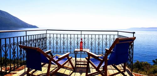 two chairs and a table on a balcony overlooking the water at Villa LeSunLuka Lefkada in Vasiliki