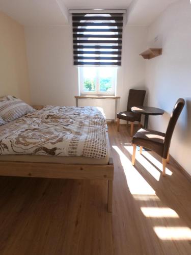 a bedroom with a bed and a chair and a window at Penzion Bejby Turnov in Turnov