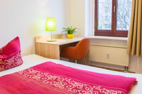 a bedroom with a bed and a desk with a lamp at Gwuni Mopera in Leipzig