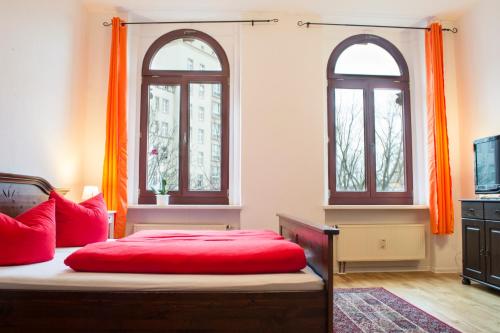 a bedroom with a bed with red pillows and two windows at Gwuni Mopera in Leipzig