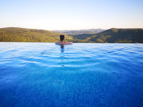 a man in a pool of water with mountains in the background at Home Andrea with infinity salty pool in Roč