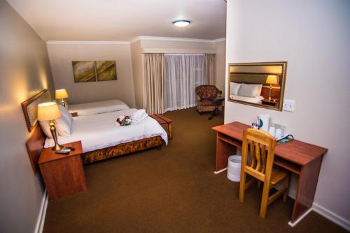 a hotel room with a bed and a desk and a bedroom at Adelante Lodge in Bloemfontein