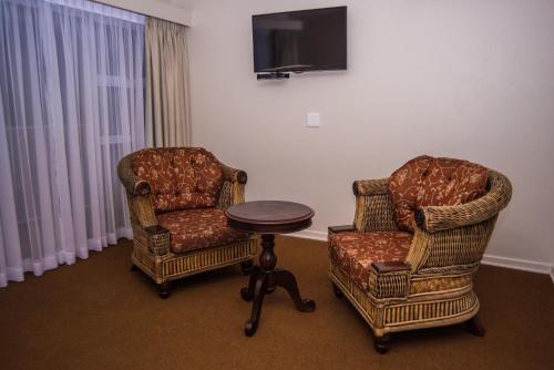 two chairs and a table and a tv in a room at Adelante Lodge in Bloemfontein