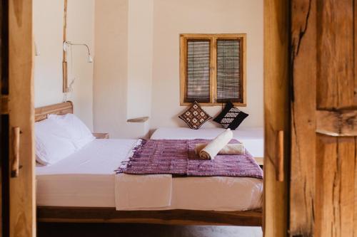 a bedroom with two beds and a window at Kalyssa Beach Bungalows in Pemuteran