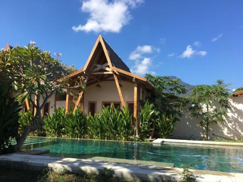 a house with a swimming pool in front of it at Kalyssa Beach Bungalows in Pemuteran