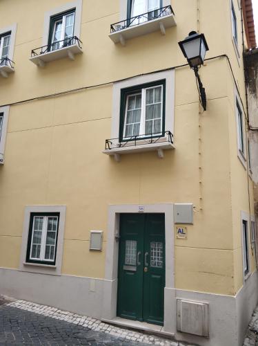 a building with a green door and two windows at Belo Apartment in Leiria