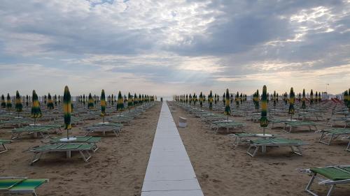eine Reihe von Tischen und Sonnenschirmen am Strand in der Unterkunft Hotel Senyor in Rimini