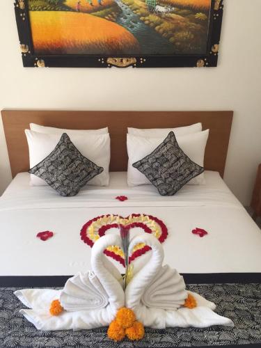two white swans are forming a heart on a bed at Pondok Serayu in Ubud