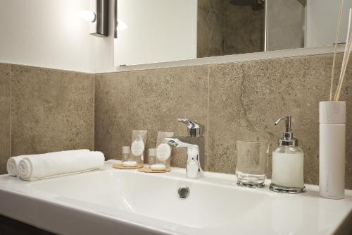 W łazience znajduje się umywalka, zestaw kosmetyków i lustro. w obiekcie Lifestyle Apartments w Puli