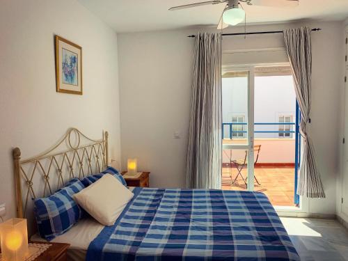 um quarto com uma cama azul e branca e uma varanda em Fantastic 3-Bedroom Holiday Home including Tennis and Pool Near Golf Course em El Portil
