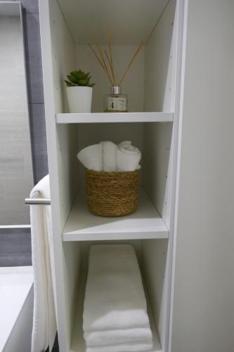 a bathroom shelf with towels and a basket of towels at Belo Apartment in Leiria