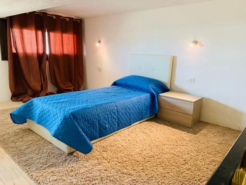a bedroom with a bed with a blue comforter at Luxar room in Assemini