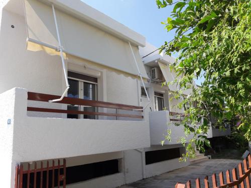 a white building with a balcony and a tree at apt 30m from beach in Amarinthos