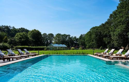 a swimming pool with chaise lounge chairs and a swimming pool at Romantik Hotel Jagdhaus Eiden am See in Bad Zwischenahn