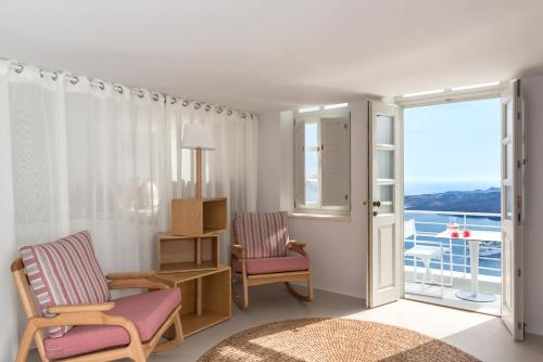 a living room with two chairs and a balcony at Nefeles Luxury Suites in Fira