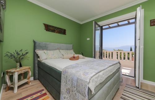a bedroom with green walls and a bed with a window at Ocean's Serenity in Supetar