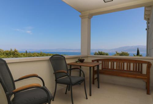 a porch with chairs and a table and a bench at Ocean's Serenity in Supetar