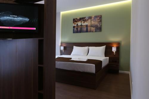 a bedroom with a bed and a flat screen tv at Kuint Hotel in Peje
