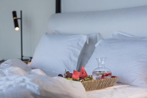 a plate of fruit on a bed with a bottle at Nefeles Luxury Suites in Fira