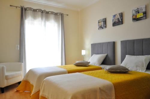 two beds in a room with a window at Casa da Villa-Grândola in Grândola