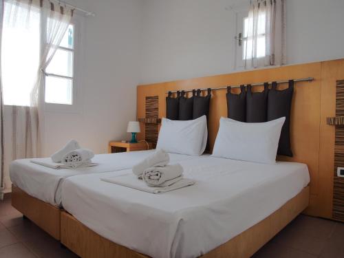 a bedroom with a large white bed with towels on it at Chaniotis Studios in Kalafatis