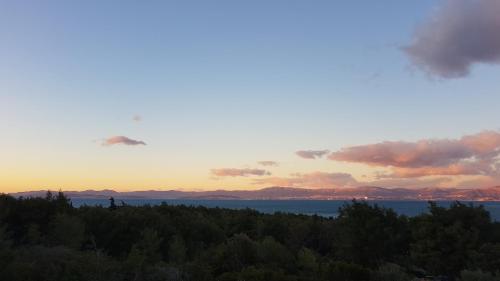 a view of the sunset from a hill with trees at Ocean's Serenity in Supetar