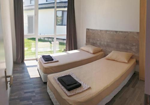 two beds in a room with a window at Karia Apartments in Shabla