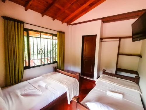 two beds in a room with a window at Casa Campestre Las Nieves in San Gil