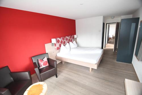a bedroom with a white bed and a red wall at Hotel Ucliva in Waltensburg