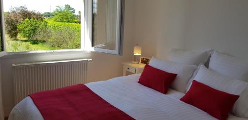 a bedroom with a bed with red pillows and a window at Chambres d'hôtes Gite Grange Debout in Beynost