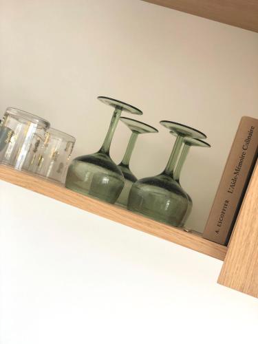 four green glass vases sitting on a wooden shelf at JACARANDA II Appartement in Mandelieu-la-Napoule