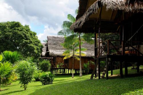 a resort with a grass roofed building with a swing at Pacaya Samiria Amazon Lodge - ALL INCLUSIVE in Nauta