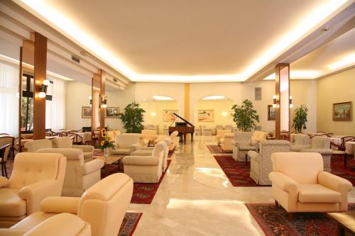 a waiting room with chairs and a grand piano at Hotel Terme Marconi in Montegrotto Terme