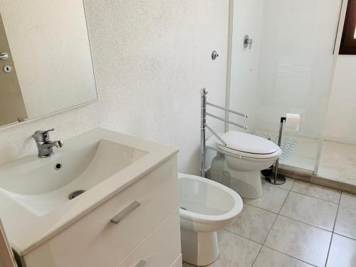 a white bathroom with a sink and a toilet at Luxar room in Assemini